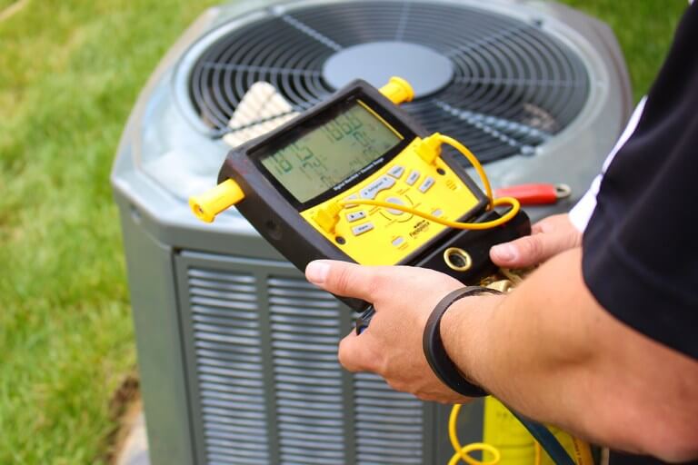 A technician inspecting an outdoor AC unit Naperville IL